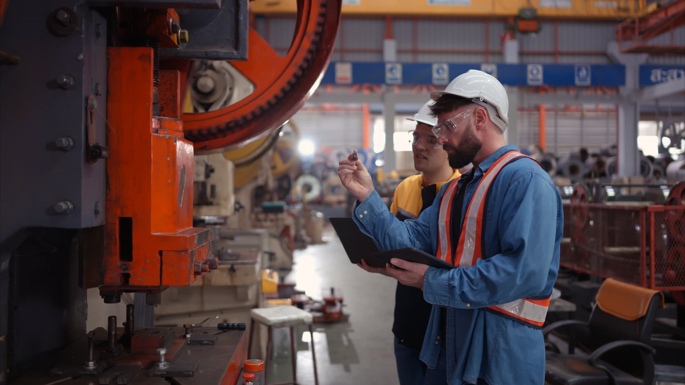 An engineer and technician discussing machinery on a factory floor